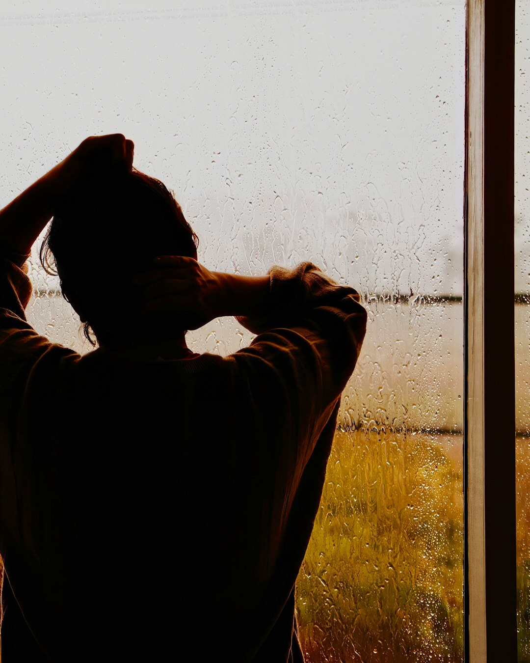 person looking out rainy window