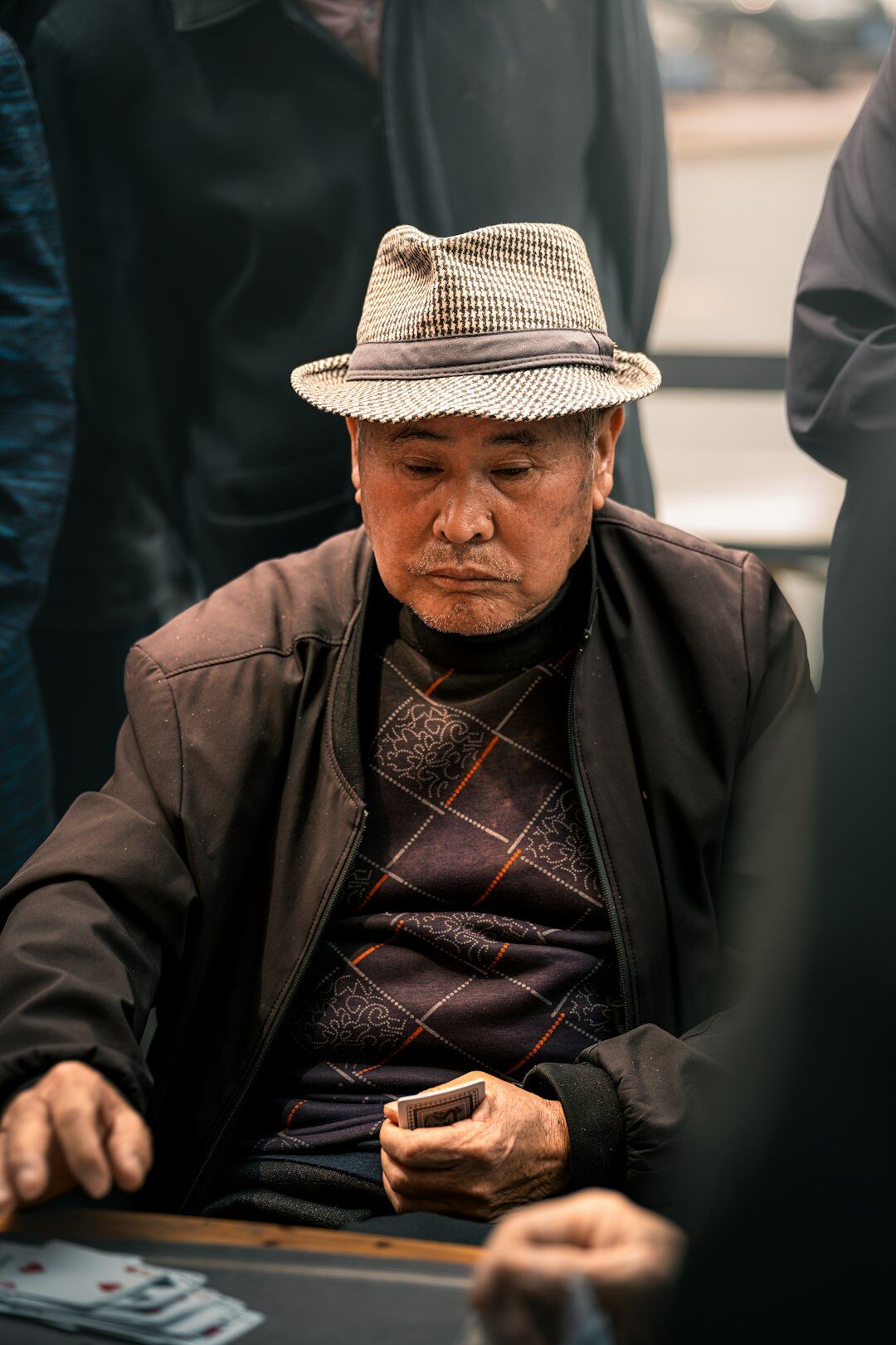 Elderly men playing cards at a wooden table and smiling